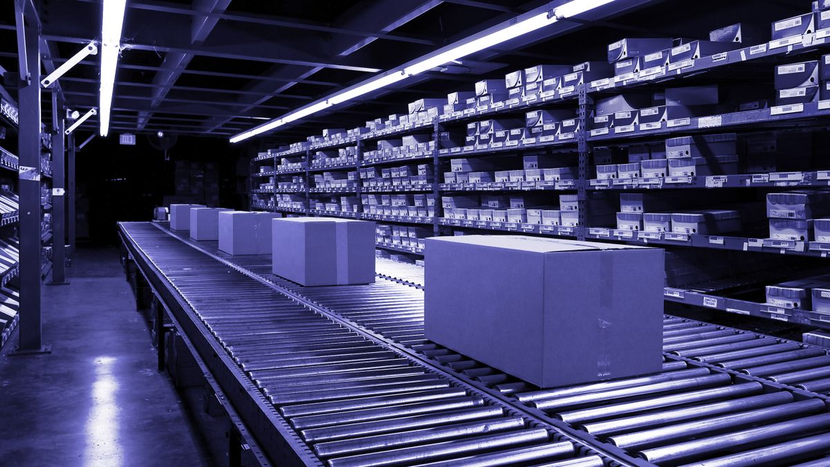 Cardboard boxes on a conveyor belt in a warehouse.